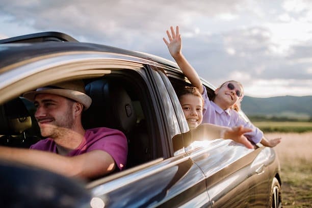 Family waving from their car on a road trip