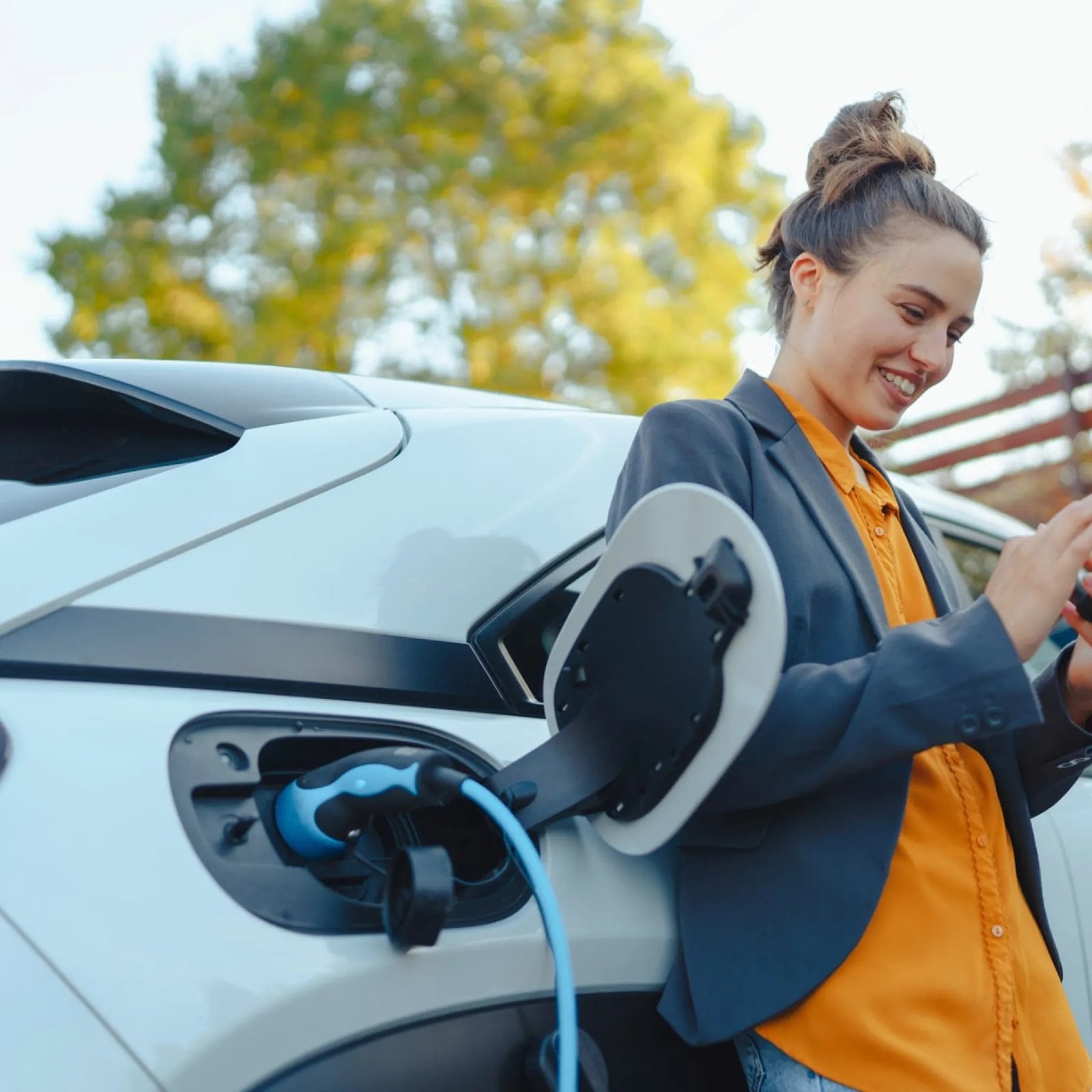 Traveler smiling at her phone while her electric car charges