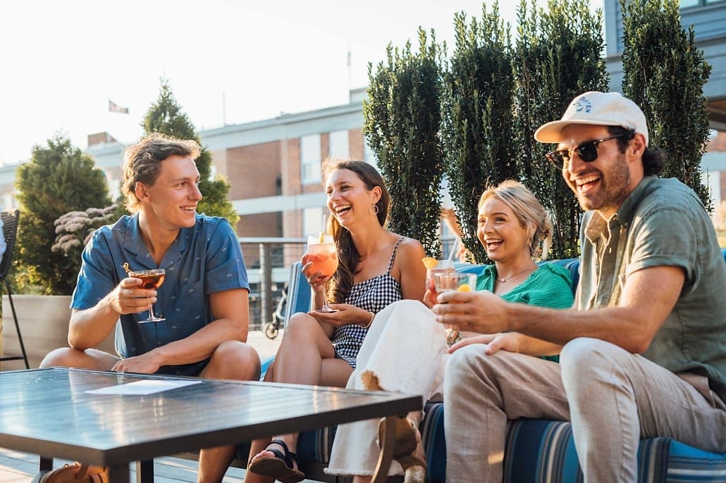 Friends laughing over drinks on a sunny patio